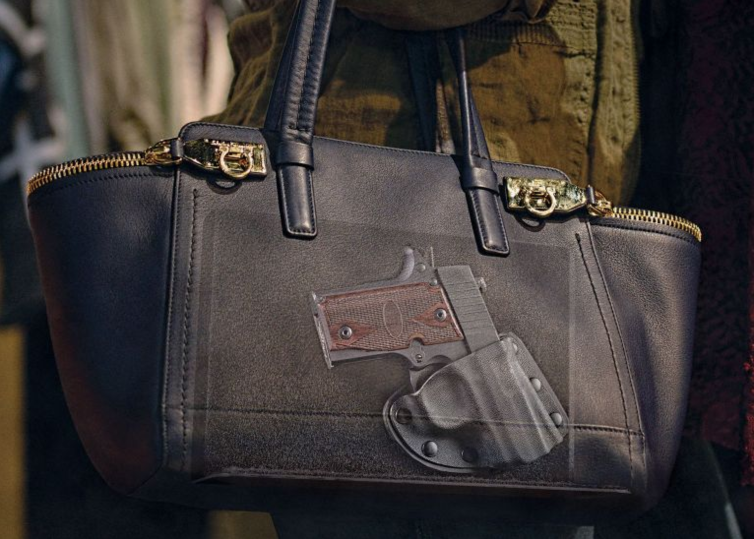 A woman carries a large purse which shows a handgun in a trigger-protected hybrid holster inside.
